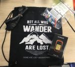 Bag that says "Not all who wander are lost" as well as GPS and cache toys